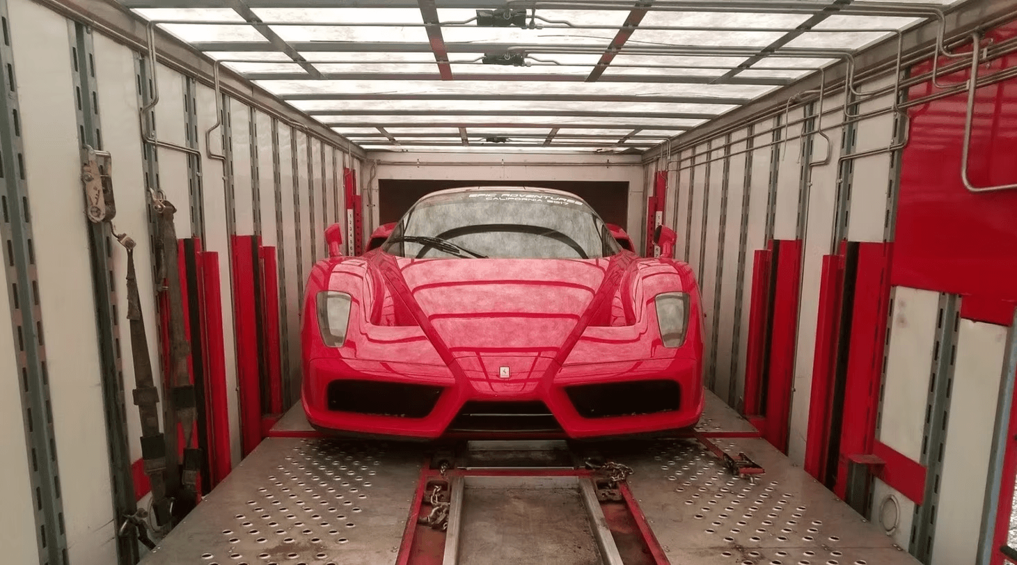 Red sports car secured inside an enclosed car carrier